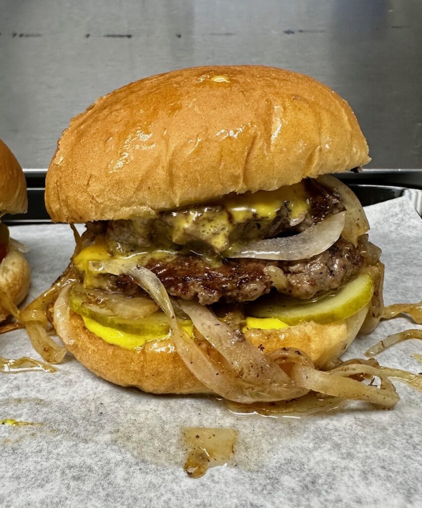 Motz's Burgers loaded slider with cheese, onions, pickles, and mustard