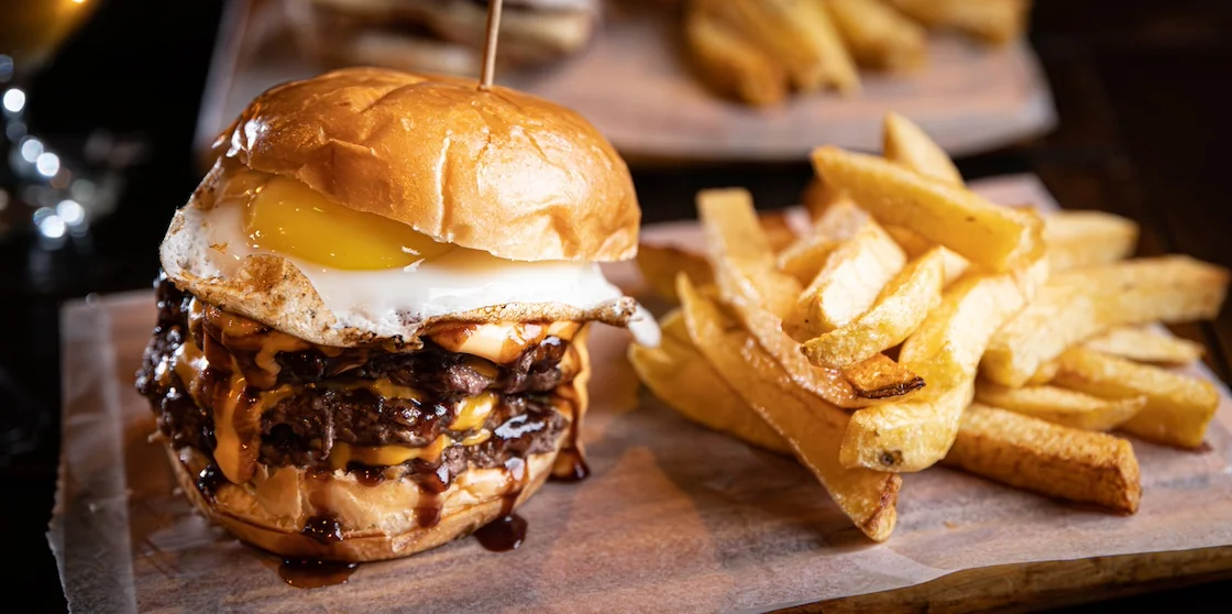 burger with fries and glass of beer and over easy egg