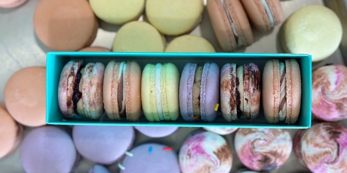 box of 6 macarons from le detroit macaron surrounded by various macaron flavors
