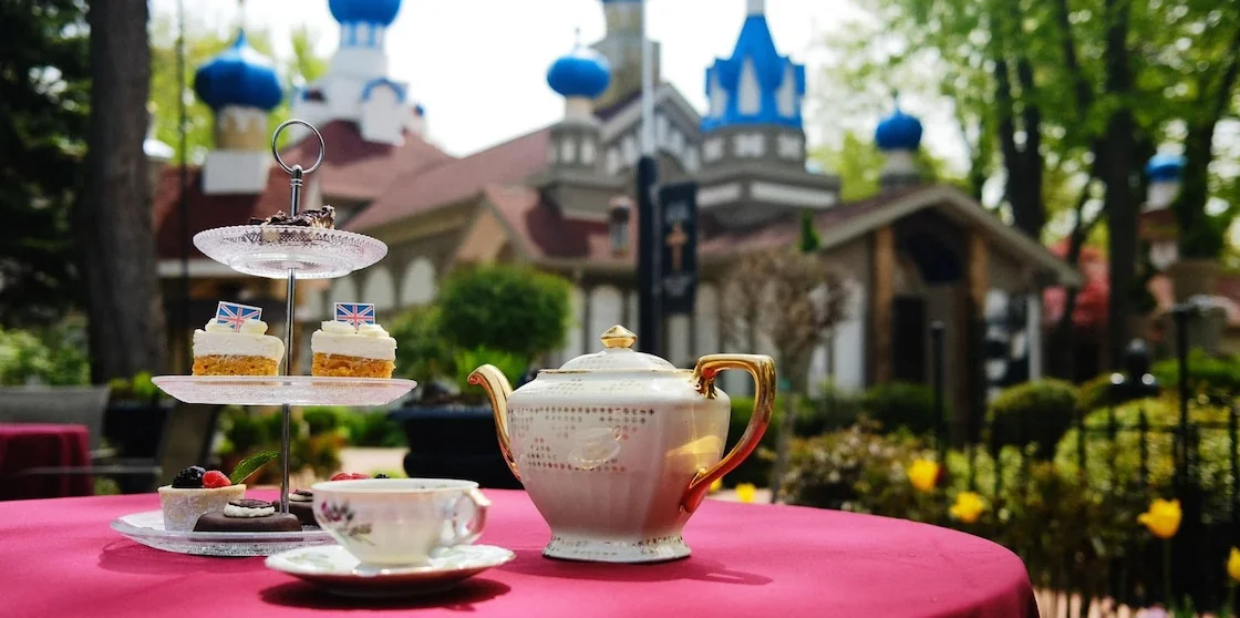 a tea pot and cup with tiered tray of pastries in the gardens of the royal eagle