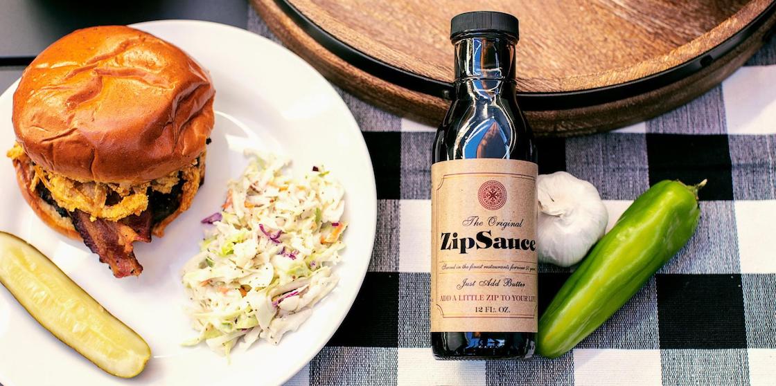 bottle of ZipSauce with plate of pulled pork, coleslaw, and a pickle