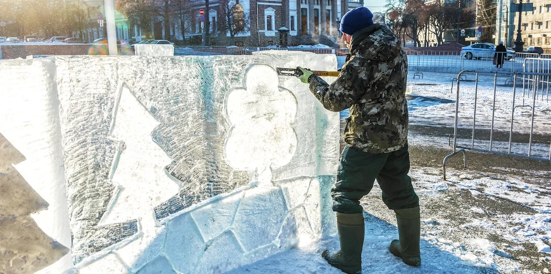 a sculptor makes patterns and ornaments on ice blocks for a winter festivals children's town.