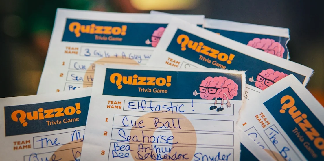 quizzo trivia sheets spread out with various written answers