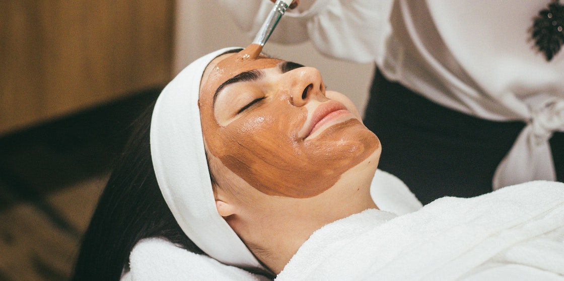 Woman receives clay mask during facial treatment