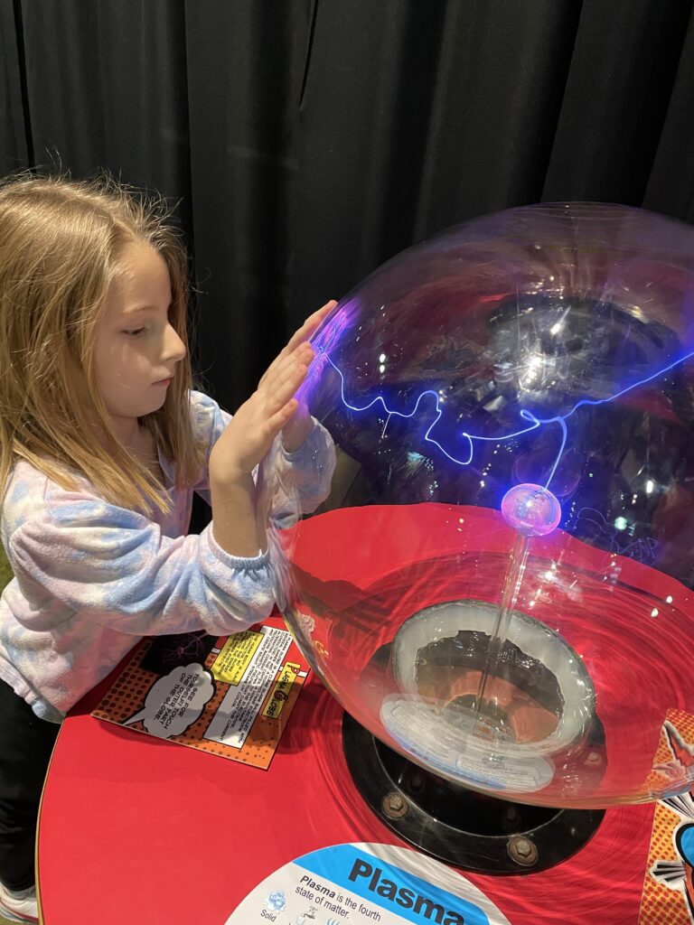 Young girl experiments with electricity exhibit at Michigan Science Center
