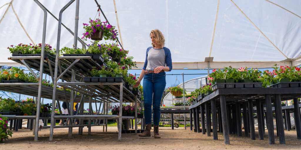 Woman walks through the aisles of Vans Valley Greenhouse selecting plants