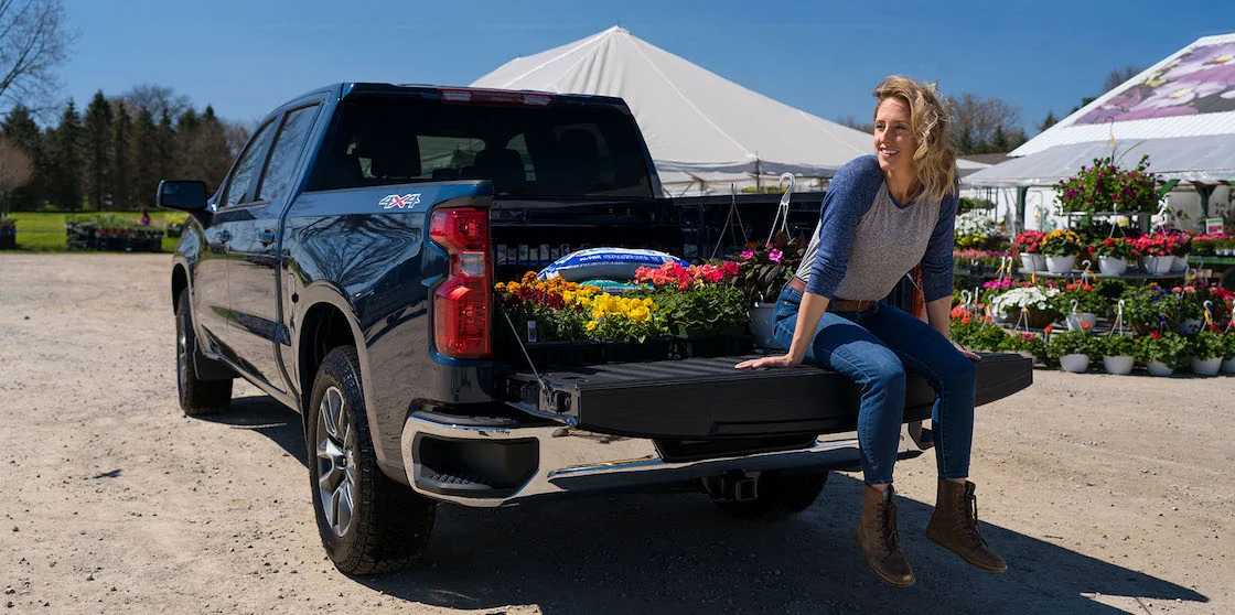 Woman sits on tailgate of Chevy Silverado