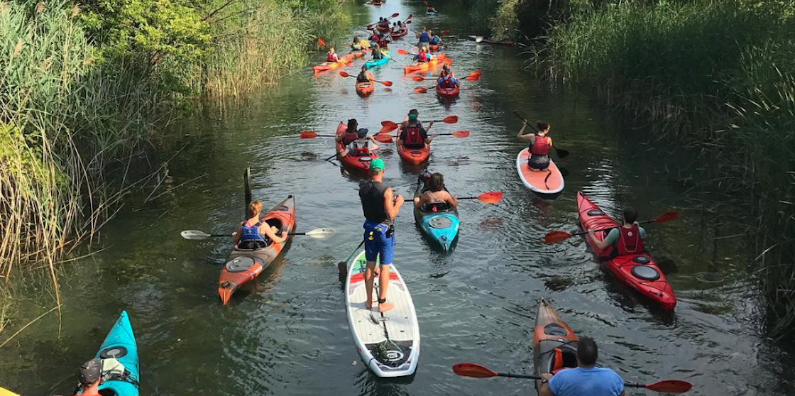 Kayakers follow a tour guide on a paddleboard