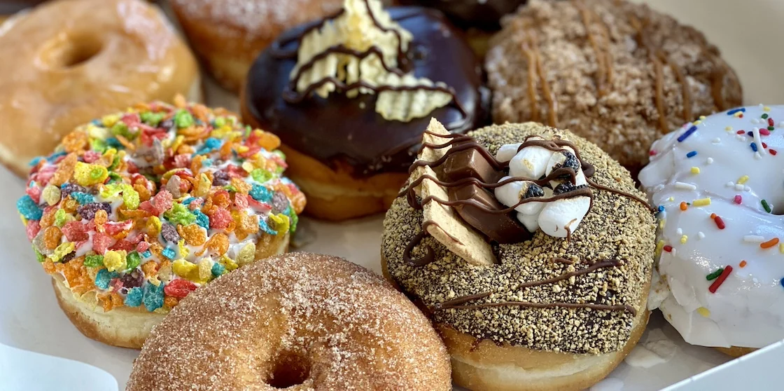 Delicious donuts (pictured in selective focus) topped with a variety of sweet and colorful toppings.