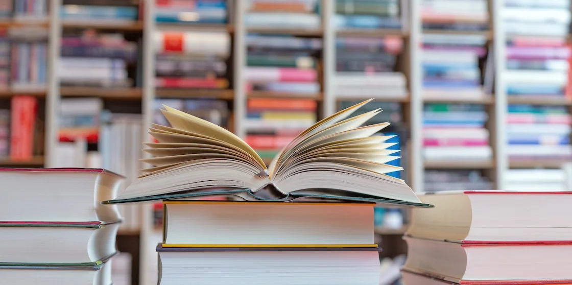 open novel on a stack of books - book shops