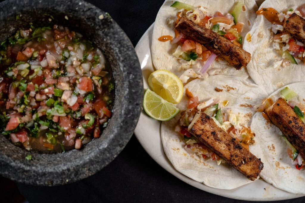 mahi mahi fish tacos from el asador with a bowl of pico de gallo