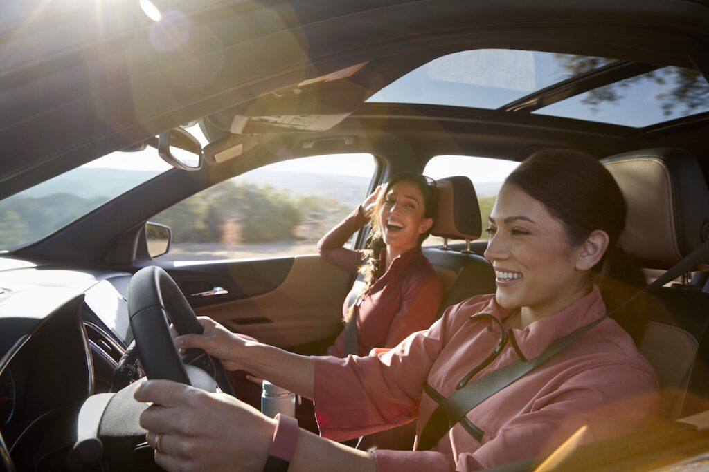 Two women laughing and smiling while driving
