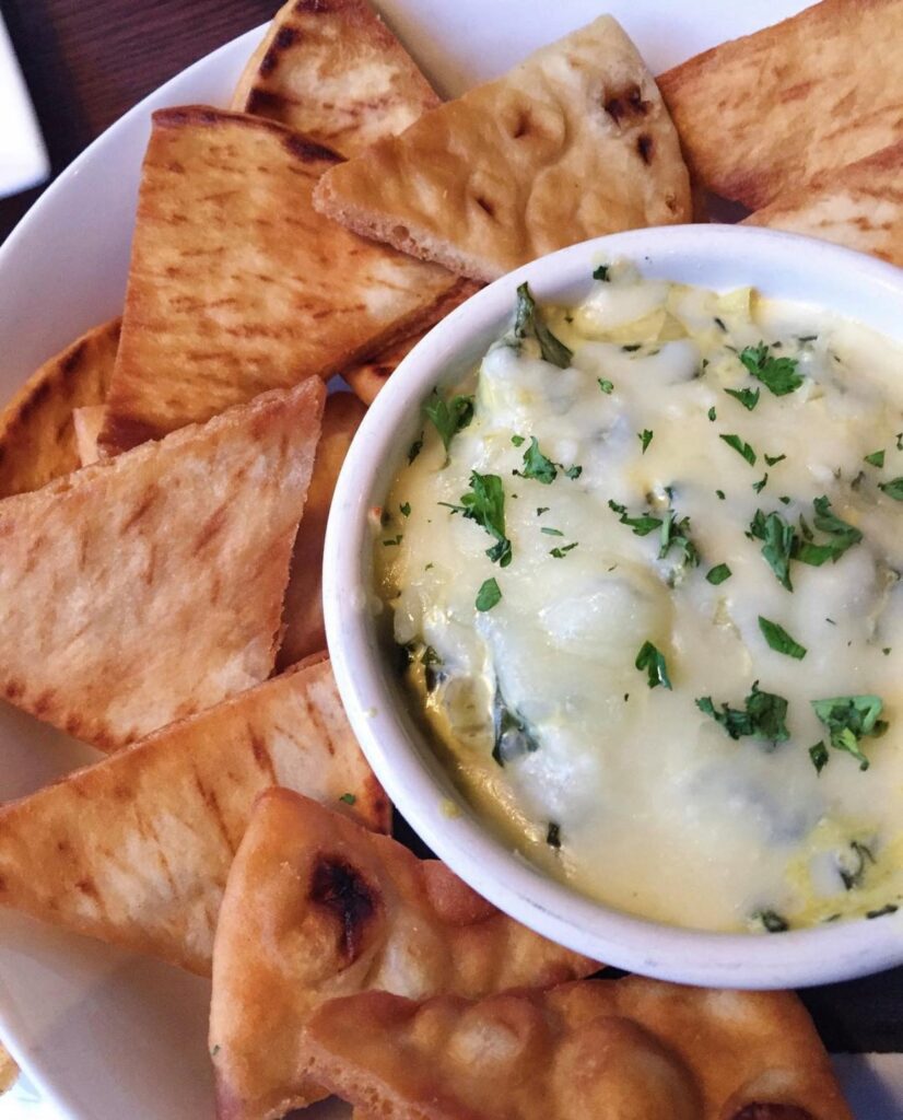 spinach dip covered with baked cheese and pita chips from The Block - dips