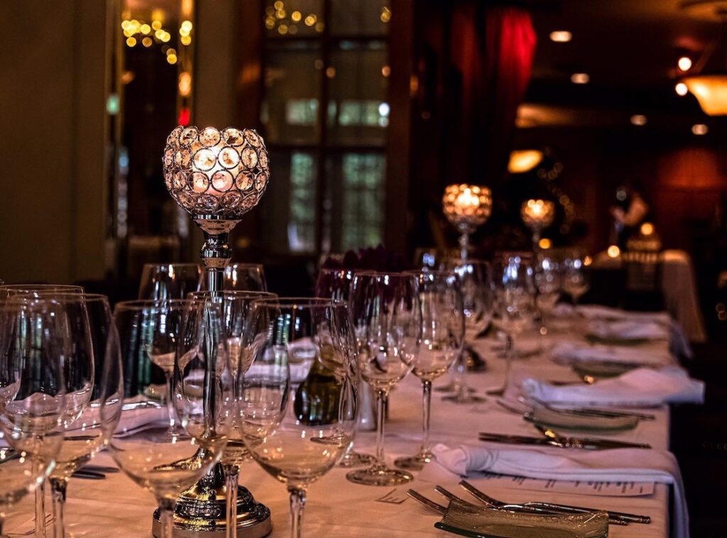 table with glasses, place settings, and menus in low lighting at cafe cortina