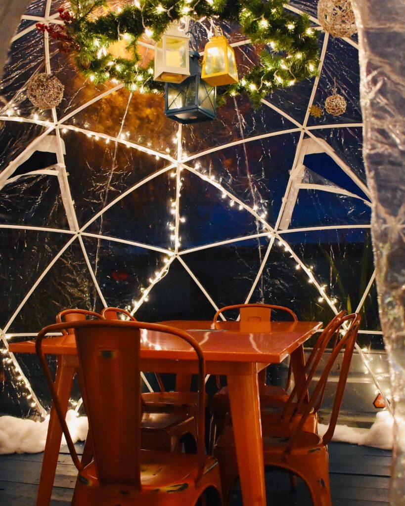 interior of detroit fleat's heated outdoor dining igloos with a table, chairs, and lights surrounding the igloo