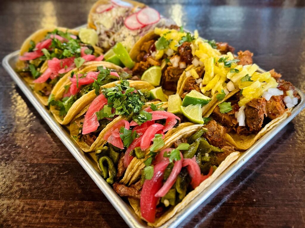 tray of 12 tacos from el arbol taqueria in brighton with various toppings with cilantro, radish, cabbage, and more