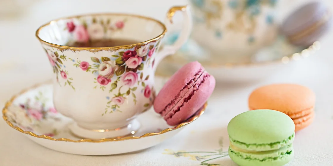 Two cups filled with tea and some macaroons