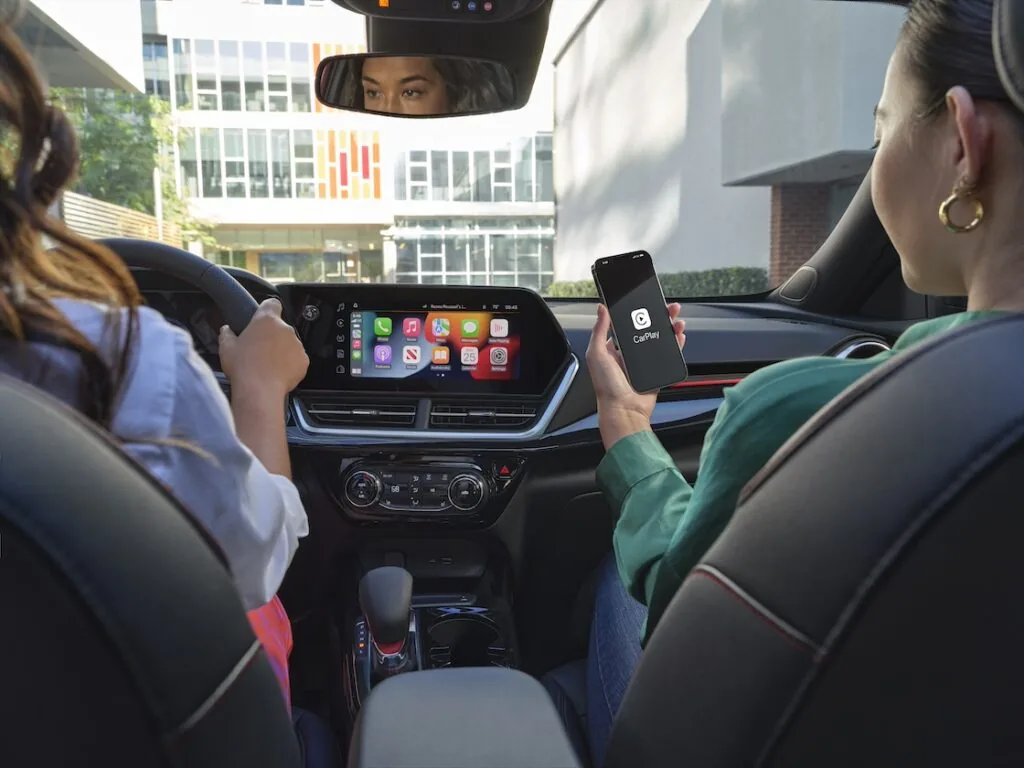 two women in a trax, with the passenger connecting to apple carplay