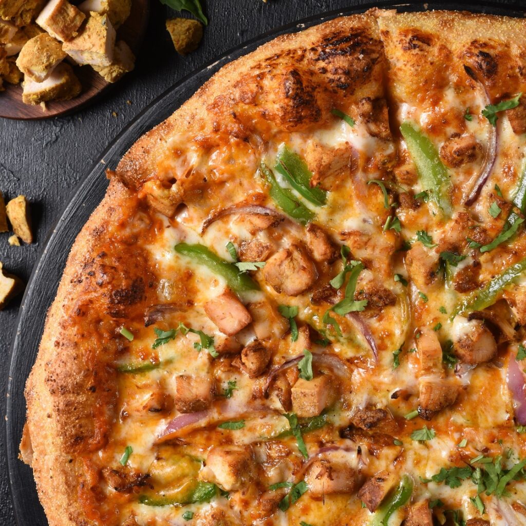 butter chicken pizza with chocjen, green peppers, onions, and more from pizzawalla's - indian cuisine
