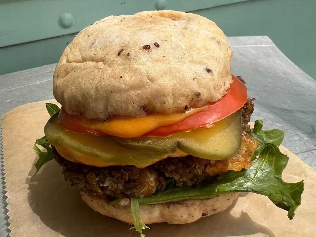 classic vegan burger with a vegan patty, vegan cheese, lettuce, tomato, and pickles
