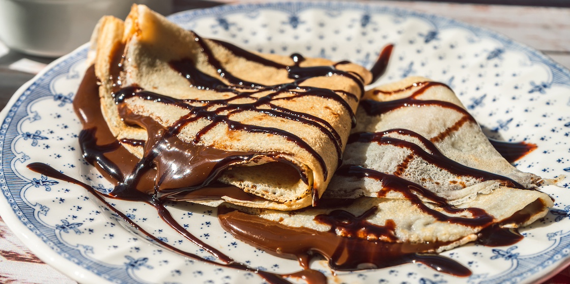 Plate two exquisite homemade crepes filled with almond cream and chocolate with chocolate threads covering.