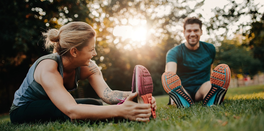 Fitness couple stretching outdoors in park. Young man and woman exercising together in morning. - spring sports