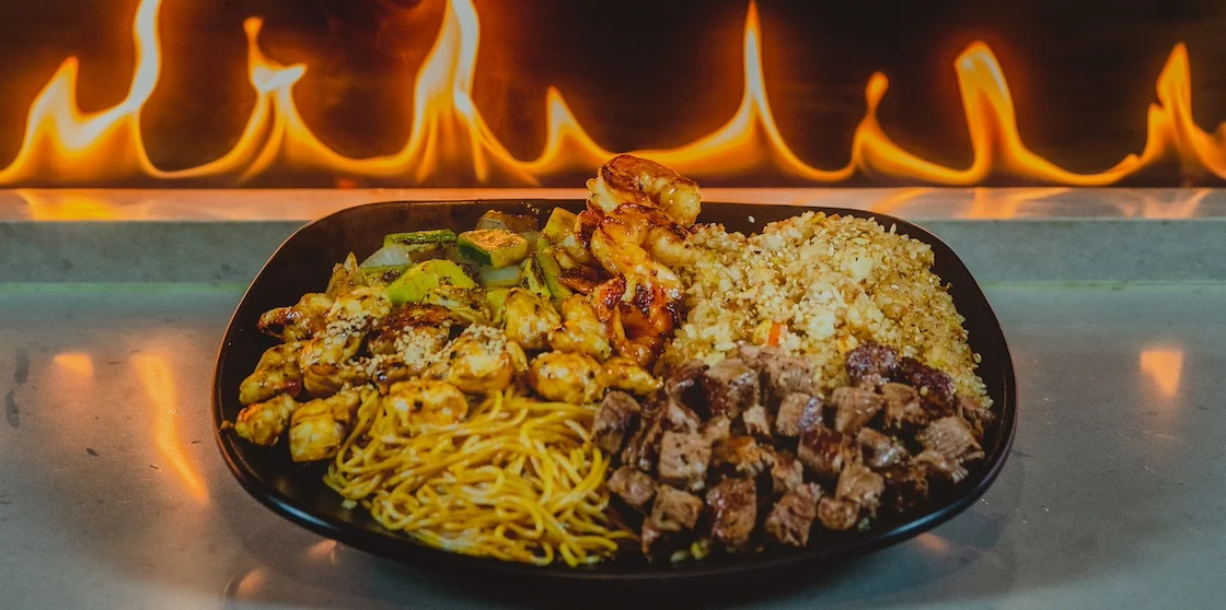 hibachi plate with a trio of meat, vegetables, rice, and noodles