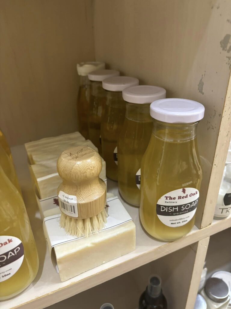 the red oak refillery dish soap bottles and a bamboo scrub brush