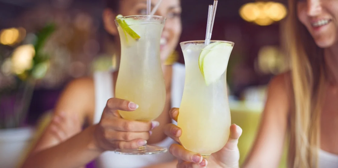 Two beautiful women having fun in a bar drinking lemonade cocktails