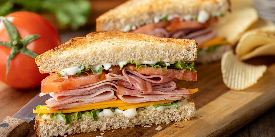 Ham sandwich with cheese, lettuce and tomato on whole grain bread