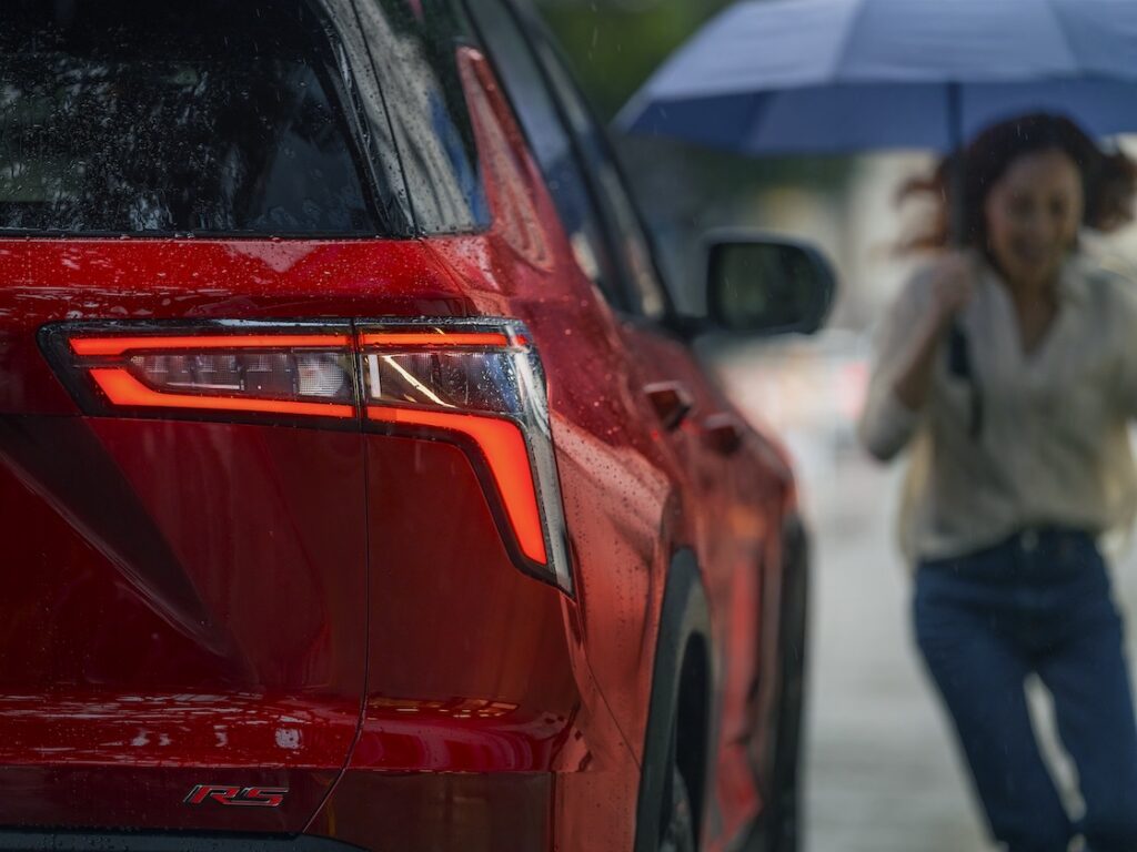 woman with umbrella running to a red equinox