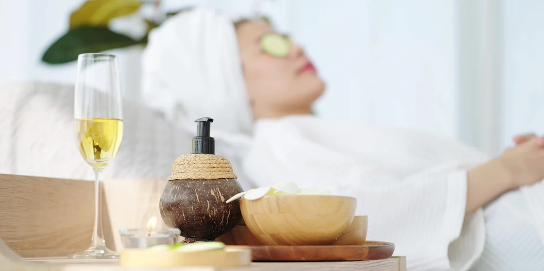 Close up spa equipment with woman laying on spa bed feeling relaxed with cucumber slices on eyes in blured background