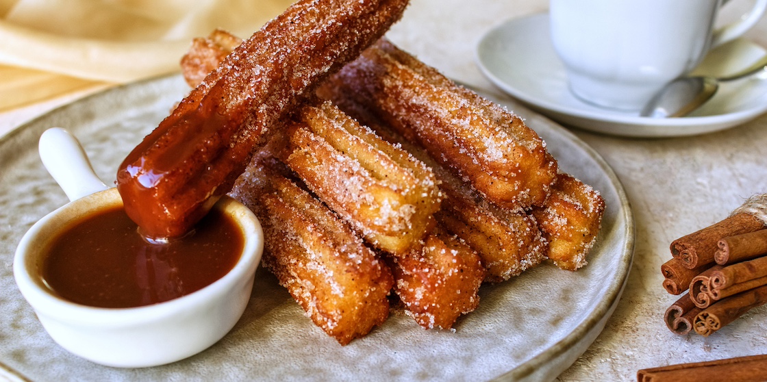 cinnamon churros on a plate with hot chocolate sauce