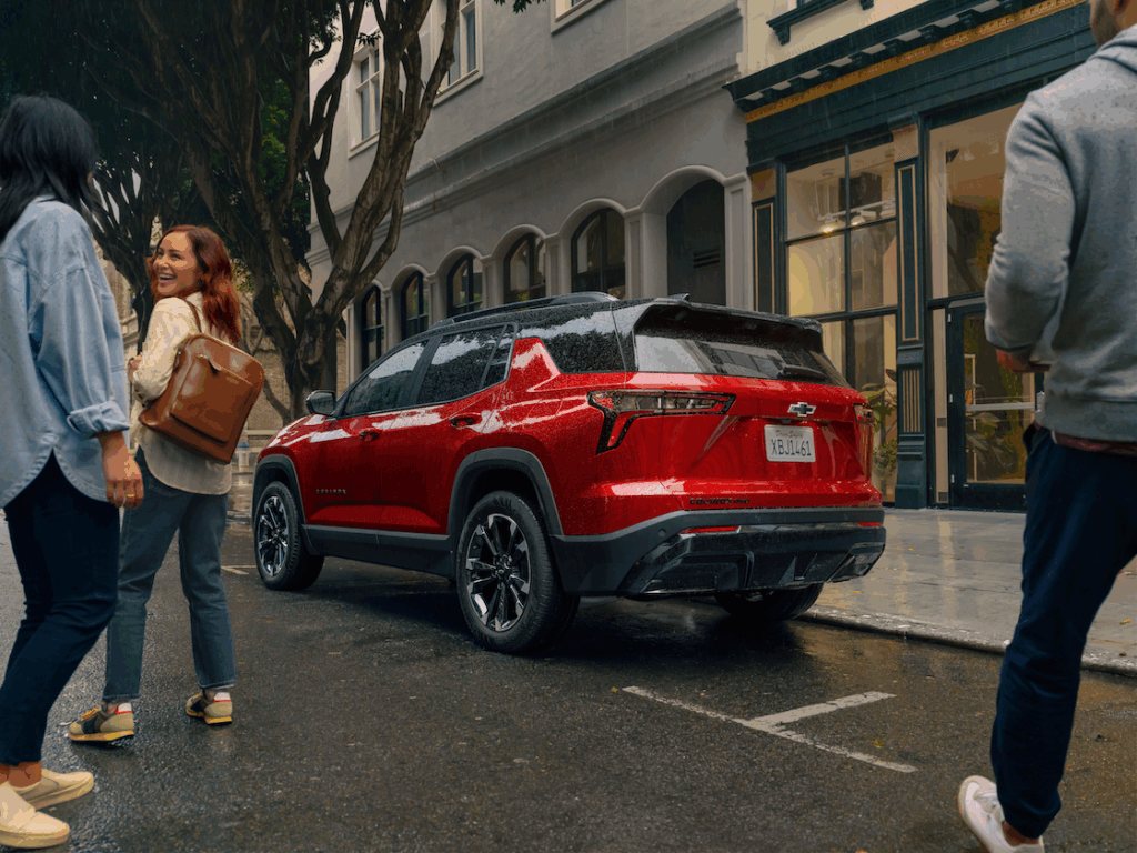 Group of Professionals around a red Chevy Equinox
