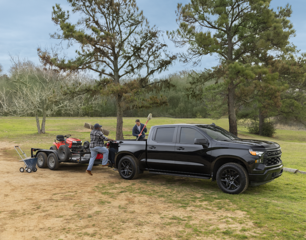 Black Silverado Crew Cab Custom with Blackout Package towing a landscaping trailer