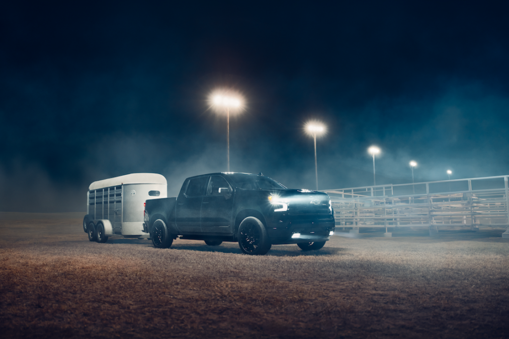 Black Silverado 1500 Crew Cab High Country towing a horse trailer at night