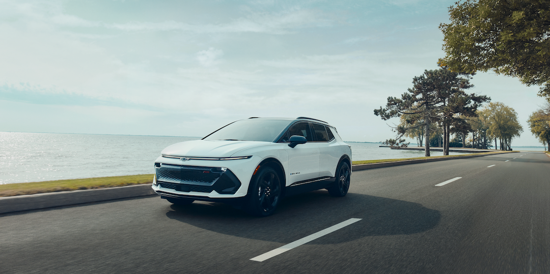 White Chevy Equinox EV driving alongside water