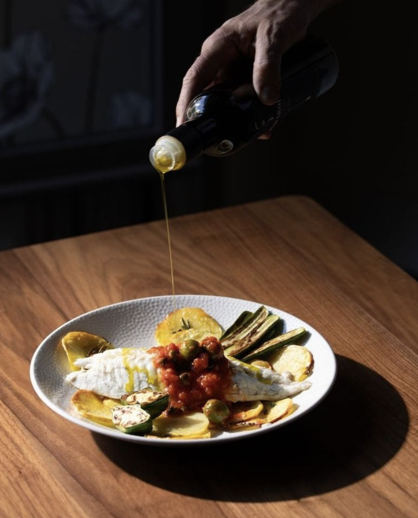 Olive oil poured over fish and grilled vegetables from e Fiori