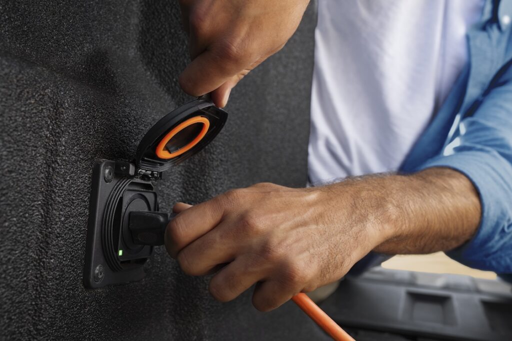 Man's hand plugging in a cord to the Colorado's bed outlet.