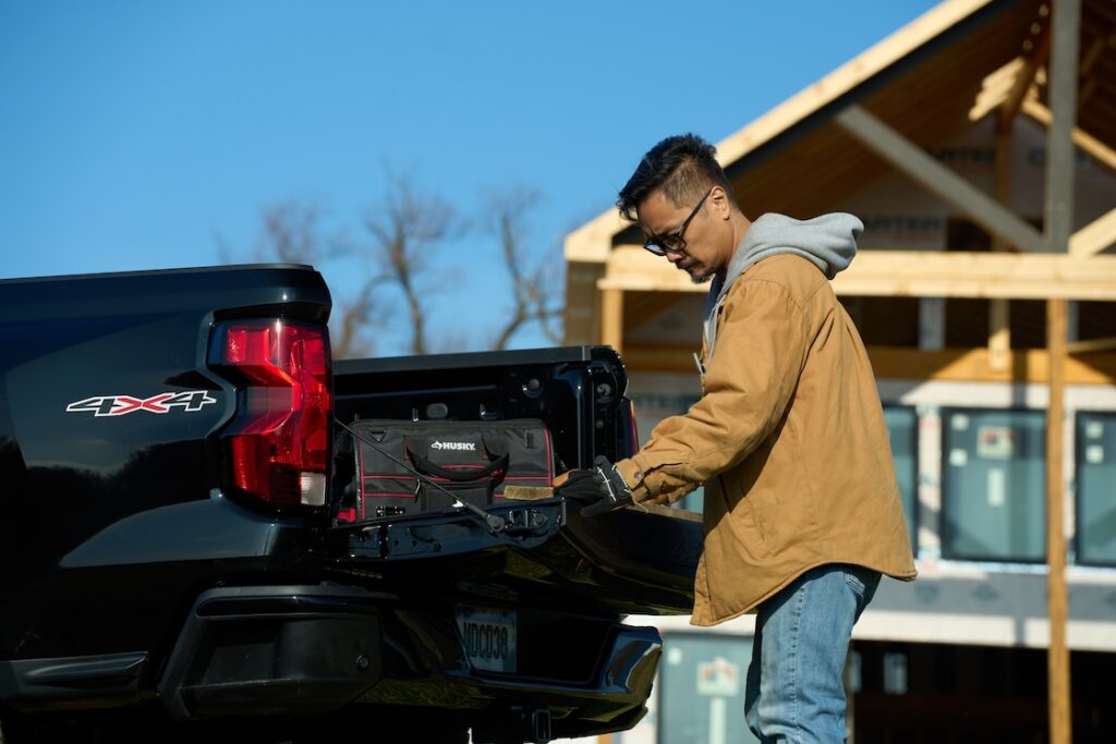 Man measuring a piece of wood on the tailgate of the Chevy Colorado, utilizing the measurement tool.